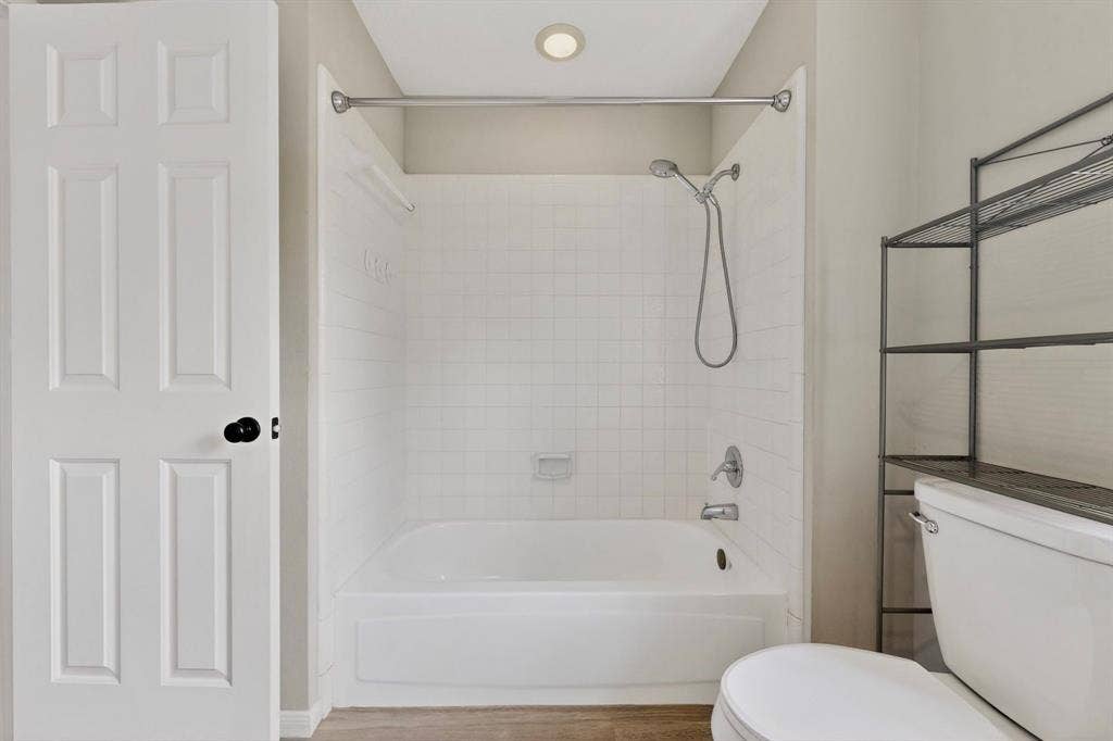 Bathtub with white subway tile surround, chrome fixtures, and a shower curtain rod