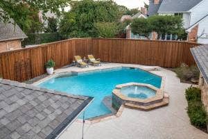 5212 Mustang Trail, Plano, TX 75093 Geometric swimming pool with an integrated octagonal spa featuring a fountain, surrounded by a concrete patio and a tall wooden privacy fence