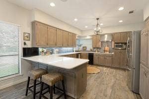 5212 Mustang Trail, Plano, TX 75093 U-shaped kitchen with wood-finish flooring, light-toned cabinetry, stainless steel appliances, and recessed lighting