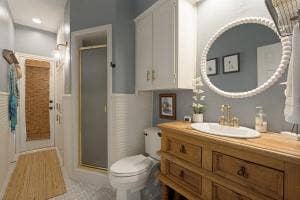 5212 Mustang Trail, Plano, TX 75093 Wood vanity with undermount sink, brass-finish faucet, and circular mirror