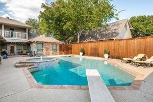 5212 Mustang Trail, Plano, TX 75093 Private backyard oasis featuring a built-in swimming pool, integrated spa with water feature, diving board, and a wood privacy fence