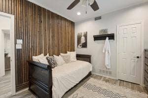 5212 Mustang Trail, Plano, TX 75093 Feature wall with vertical wood paneling, wood-finish flooring, ceiling fan with integrated lighting, and recessed lighting
