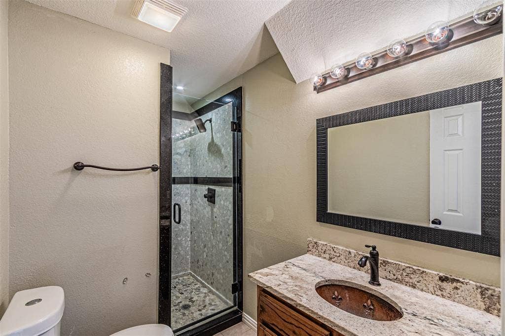 8808 Sylvan Court, Fort Worth, TX 76120 Walk-in shower with glass enclosure and pebble floor