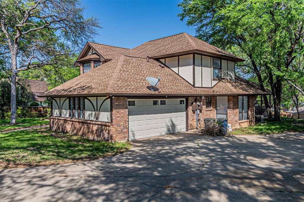 8808 Sylvan Court, Fort Worth, TX 76120 Two-story property featuring a brick and siding exterior, multi-gabled roof, and attached two-car garage