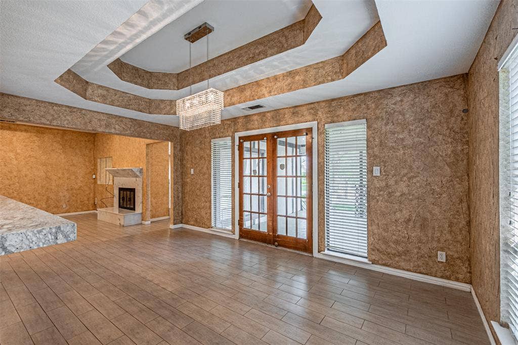 8808 Sylvan Court, Fort Worth, TX 76120 Tray ceiling with recessed lighting, wood-finish flooring, built-in fireplace, and double French doors