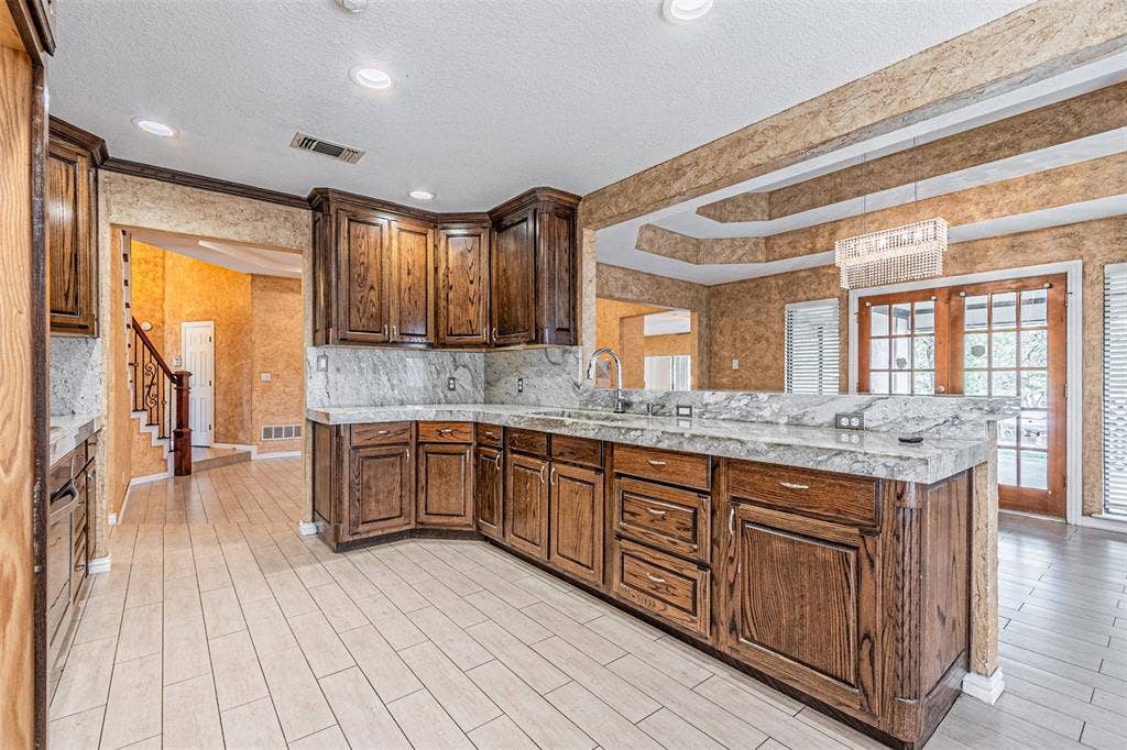 8808 Sylvan Court, Fort Worth, TX 76120 Kitchen featuring wood cabinetry, stone countertops, integrated sink, and recessed lighting