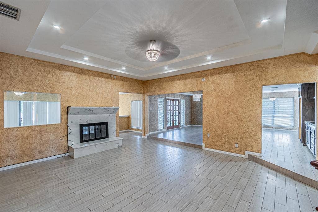 8808 Sylvan Court, Fort Worth, TX 76120 Recessed ceiling lighting, decorative ceiling fixture, tiled flooring, built-in fireplace with a stone surround, and an open doorway