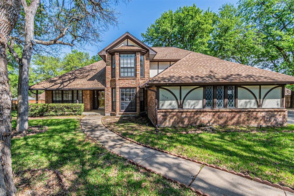 8808 Sylvan Court, Fort Worth, TX 76120 Brick exterior with a prominent bay window, gabled roofline, and an inviting pathway