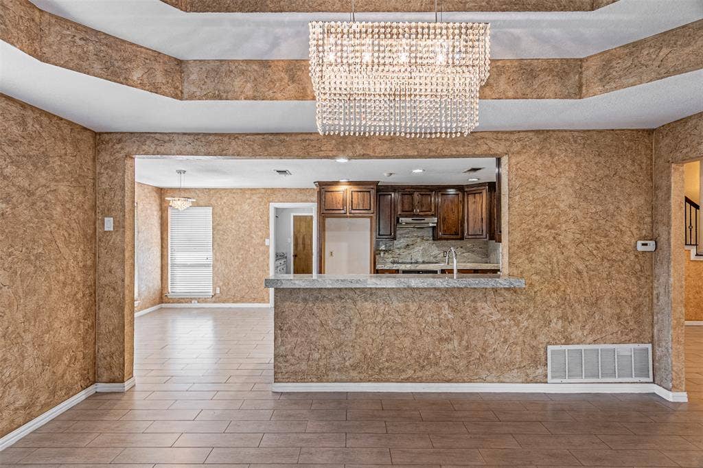 8808 Sylvan Court, Fort Worth, TX 76120 Recessed ceiling with an ornamental chandelier, tile flooring, and a kitchen pass-through with a breakfast bar