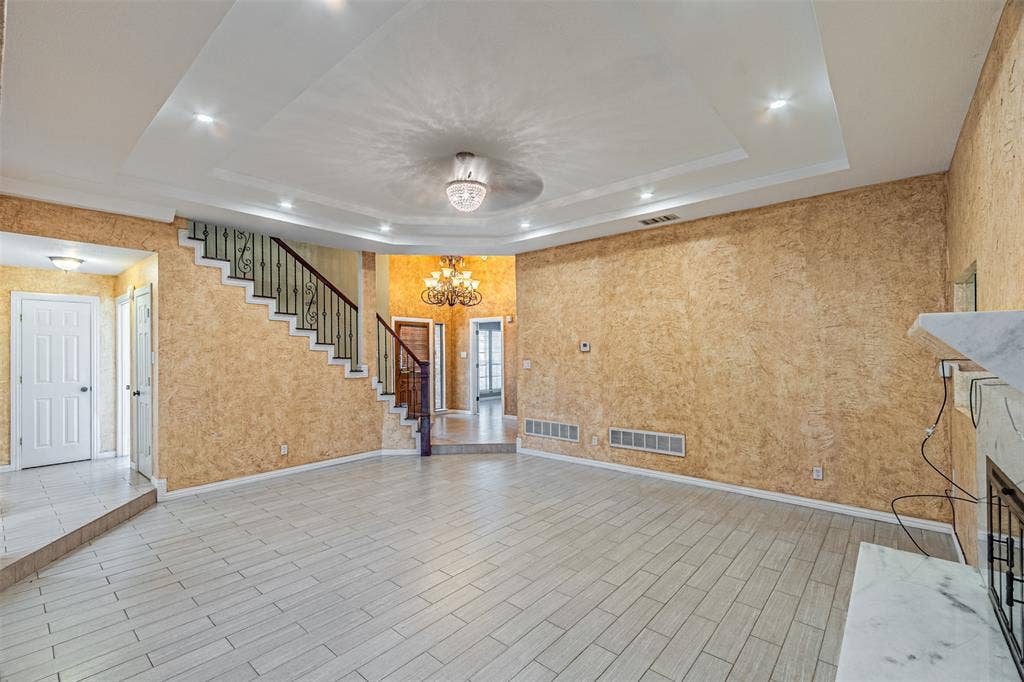 8808 Sylvan Court, Fort Worth, TX 76120 Recessed lighting, tray ceiling, tile flooring, wrought iron staircase railing, and a decorative chandelier