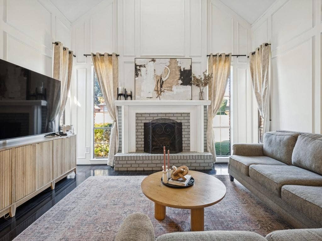 5730 Winding Woods Trail, Dallas, TX 75227 Vaulted ceilings with floor-to-ceiling wainscoting, fireplace with a painted brick surround and wood mantel, and dark-toned flooring