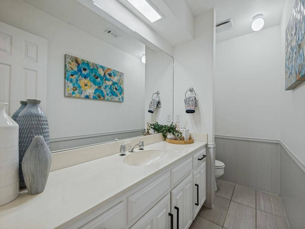 5730 Winding Woods Trail, Dallas, TX 75227 Bathroom featuring a vanity with a light-toned countertop, under-mount sink, matte black hardware, floor-to-ceiling mirror, and ceramic tile flooring