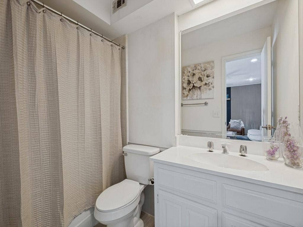 5730 Winding Woods Trail, Dallas, TX 75227 White vanity with a solid-surface countertop and integrated oval sink, paired with a full-width vanity mirror and chrome-finish hardware