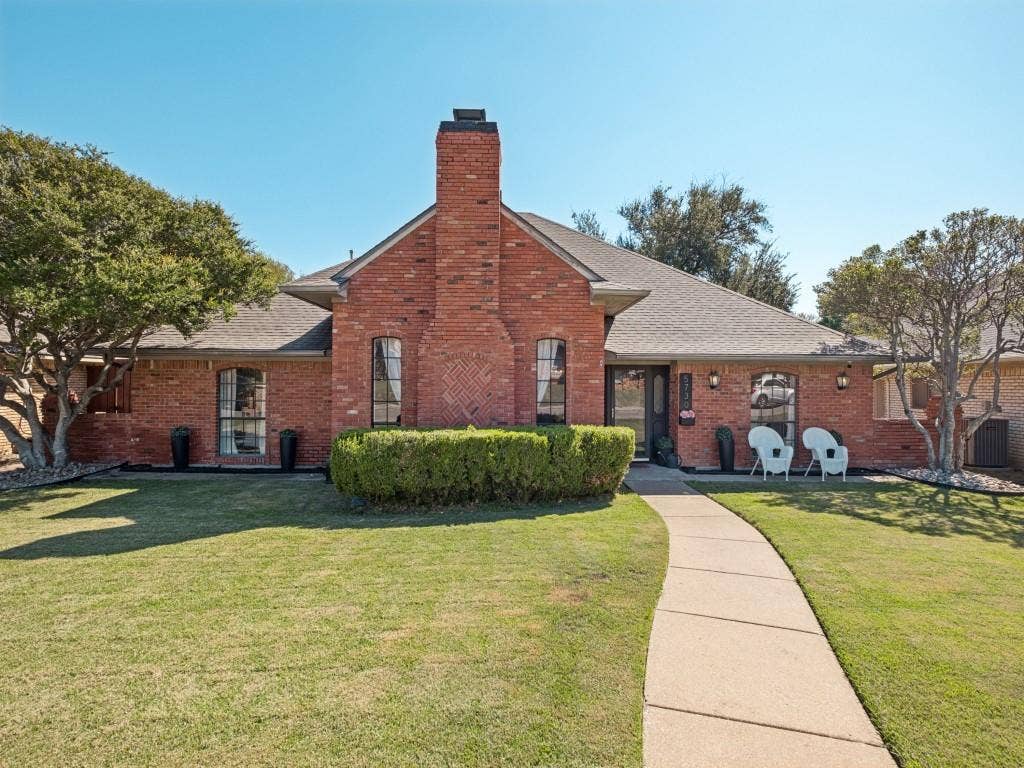5730 Winding Woods Trail, Dallas, TX 75227 Traditional brick exterior featuring an arched brick chimney, intricate masonry detail, arched windows, and a paved walkway