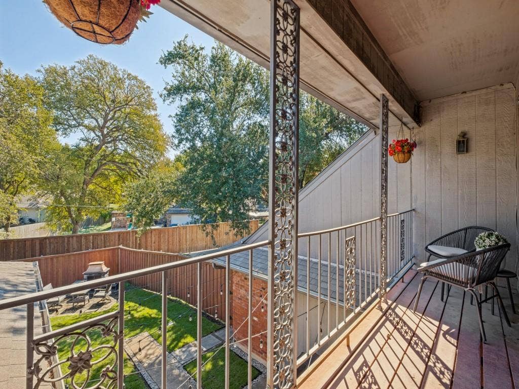 5730 Winding Woods Trail, Dallas, TX 75227 Covered balcony with decorative metal railings and vertical support columns overlooking a fenced backyard with mature trees