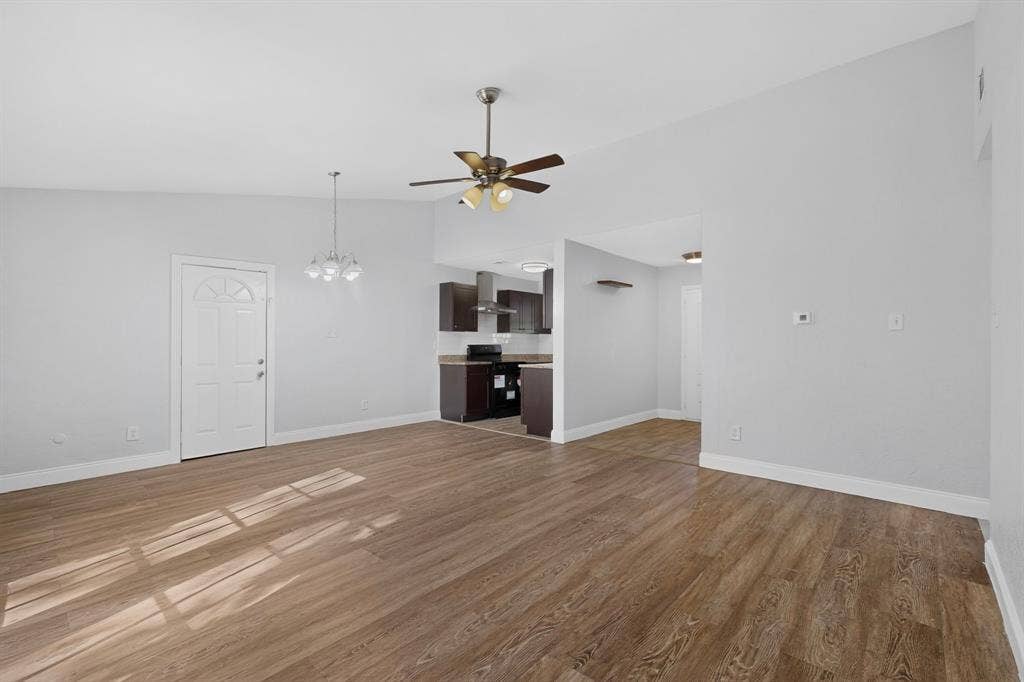1512 Bay Shore Drive, Garland, TX 75040 Open-concept area featuring vaulted ceilings, wood-finish flooring, a ceiling fan with integrated lighting, and a multi-pendant light fixture