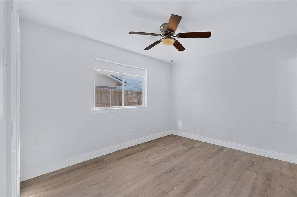 1512 Bay Shore Drive, Garland, TX 75040 Primary bedroom featuring wood-finish flooring, a ceiling fan with light fixture, and a sliding window