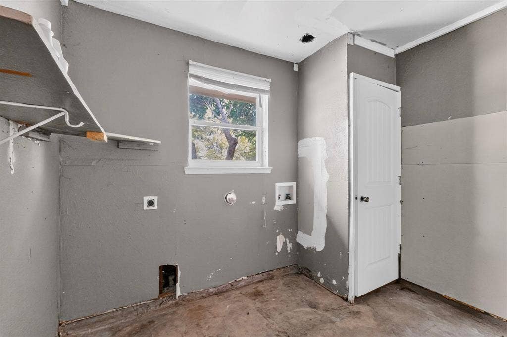 1512 Bay Shore Drive, Garland, TX 75040 Garage featuring a single-hung window, a white arched-panel door, and wall-mounted shelving