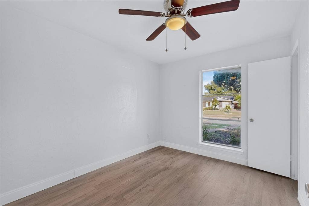 1512 Bay Shore Drive, Garland, TX 75040 Bedroom featuring wood-finish flooring, smooth-finish walls, a single-hung window, and an integrated ceiling fan with light fixture