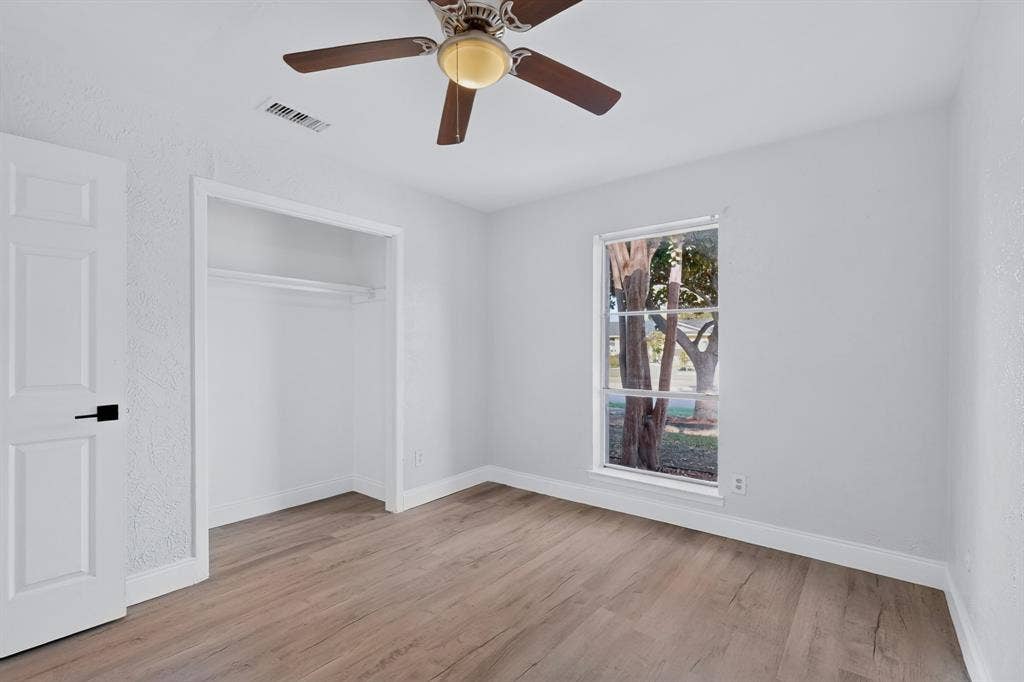 1512 Bay Shore Drive, Garland, TX 75040 Primary bedroom featuring wood-finish flooring, a ceiling fan with integrated lighting, a reach-in closet, and a single-pane window