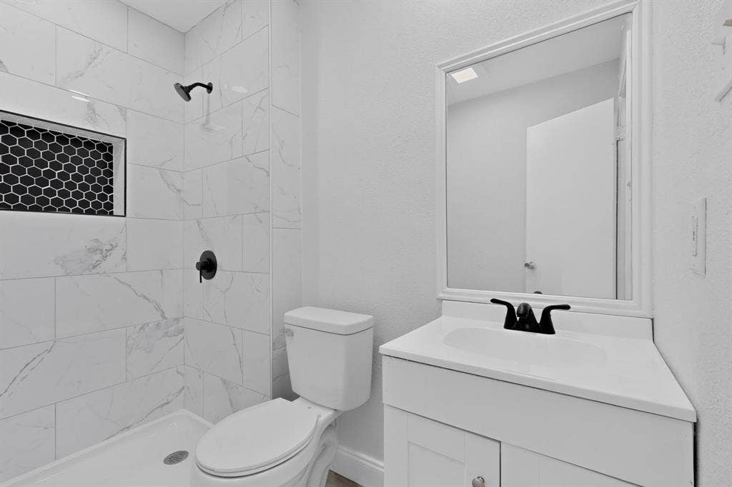 1512 Bay Shore Drive, Garland, TX 75040 Bathroom featuring a shower with white large-format tile, a black hexagonal tile inset, and a matte black shower fixture