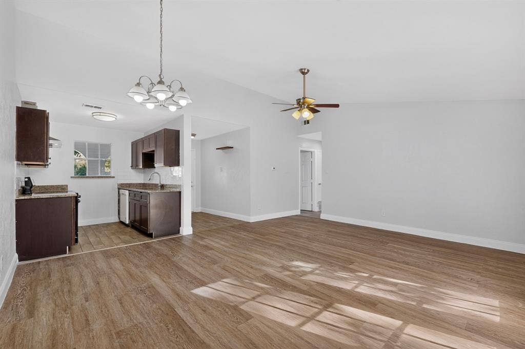 1512 Bay Shore Drive, Garland, TX 75040 Open-concept area featuring wood-finish flooring, dark cabinetry, stone-surface countertops, a multi-bulb chandelier, and a ceiling fan