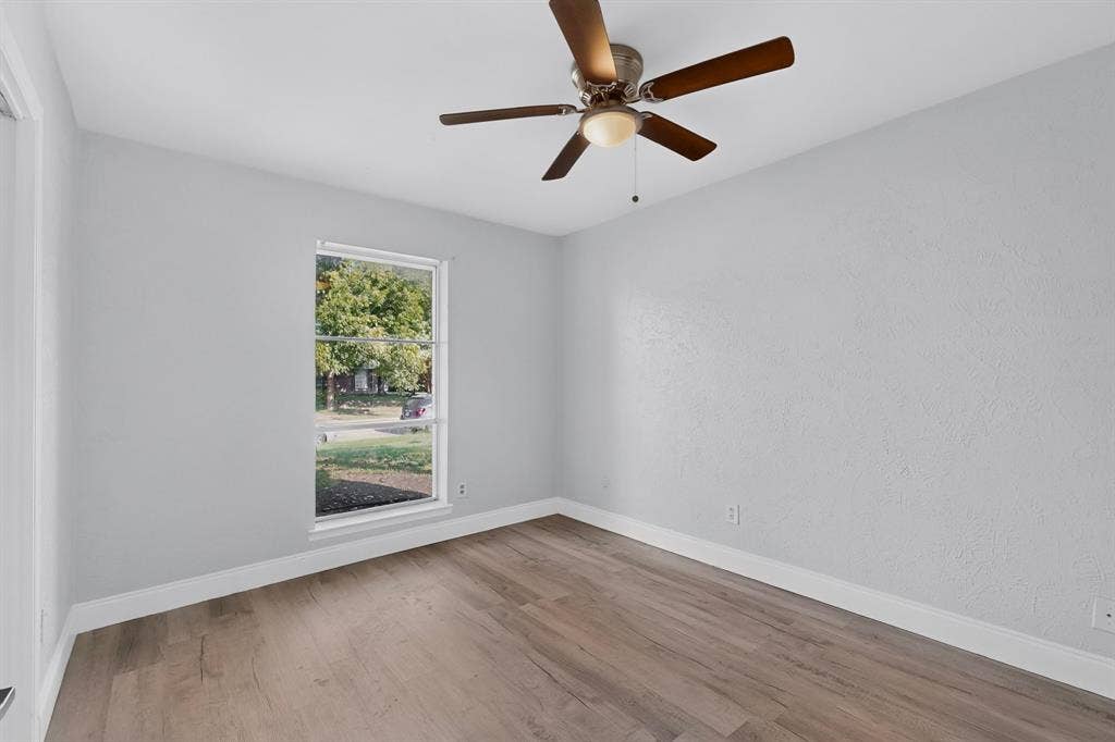 1512 Bay Shore Drive, Garland, TX 75040 Bedroom featuring wood-finish flooring, light-toned wall finishes, a multi-pane window, and a ceiling-mounted fan with integrated lighting