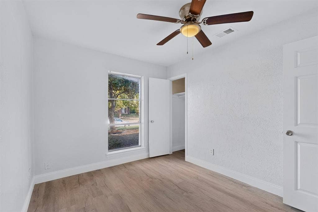 1512 Bay Shore Drive, Garland, TX 75040 Bedroom featuring wood-finish flooring, textured walls, a single-hung window, a ceiling fan with integrated light fixture, and a built-in closet