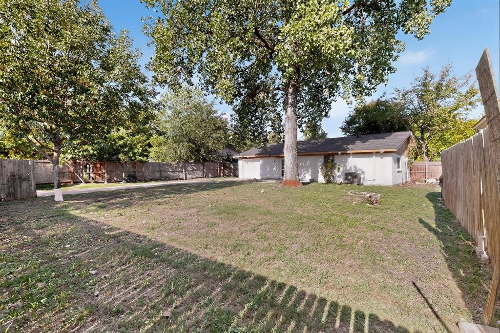 1512 Bay Shore Drive, Garland, TX 75040 Expansive backyard featuring a large grass lawn, mature trees, and wooden perimeter fencing