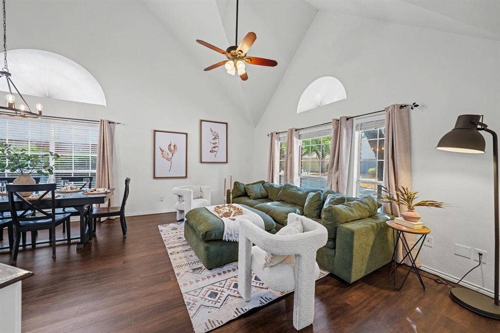 Vaulted ceiling with a ceiling fan, arched transom windows, wood-finish flooring, and a multi-light chandelier