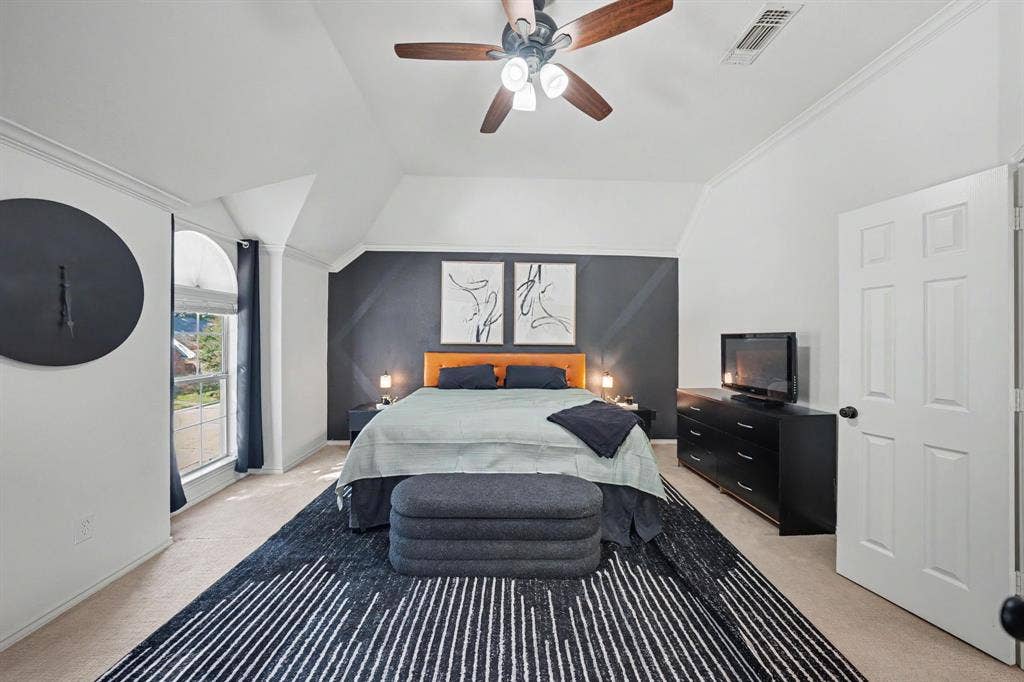 Vaulted ceiling with crown molding, ceiling fan with wood-finish blades, and recessed lighting