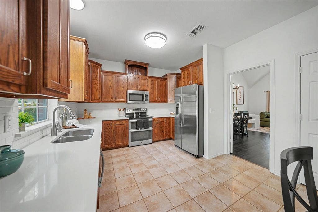 Kitchen featuring wood cabinetry, white countertops, stainless steel appliances, and tile flooring