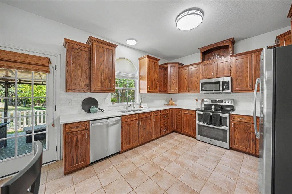 Kitchen featuring wood cabinetry, white countertops, tile flooring, and stainless steel appliances