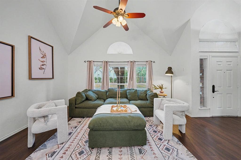Vaulted ceiling, ceiling fan, wood-finish flooring, white paneled door, and a transom window with side lights