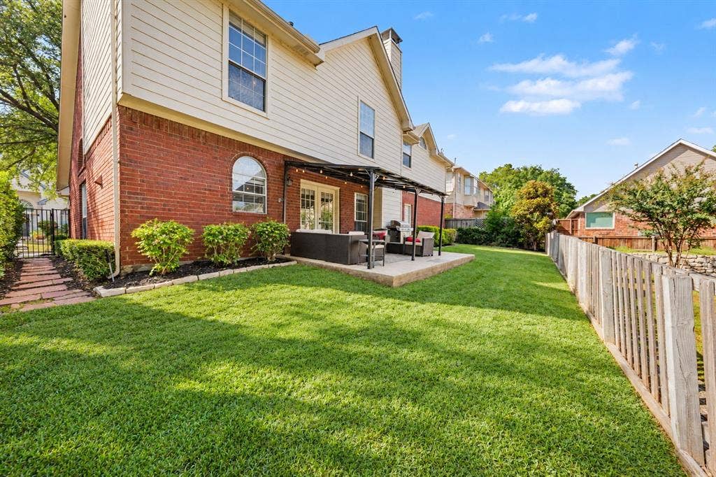 Expansive lawn with a wooden privacy fence and a brick and siding exterior