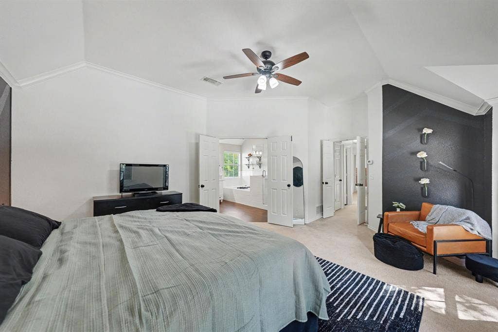Vaulted ceiling, ceiling fan, crown molding, white walls, and light carpeting
