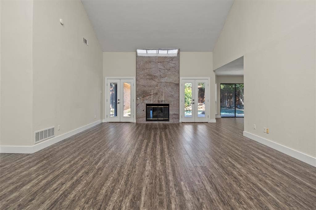 Vaulted ceilings, wood-finish flooring, and a stone-clad fireplace with a recessed firebox