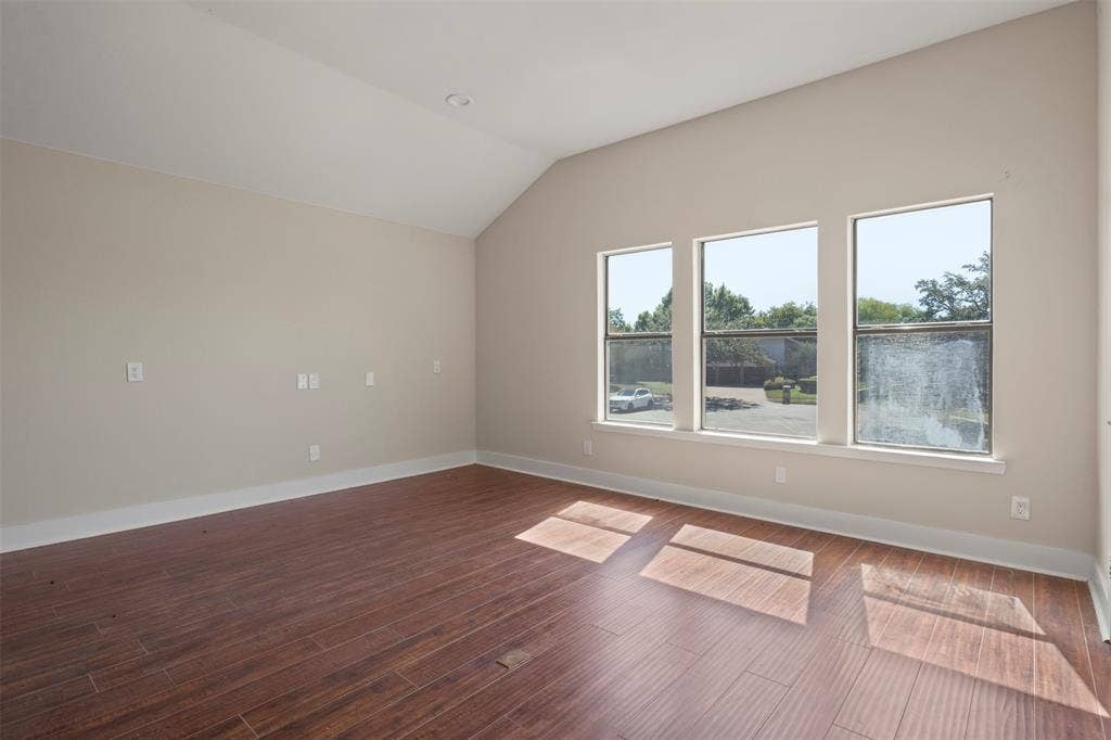 Wood-finish flooring, vaulted ceiling, recessed lighting, and three large windows