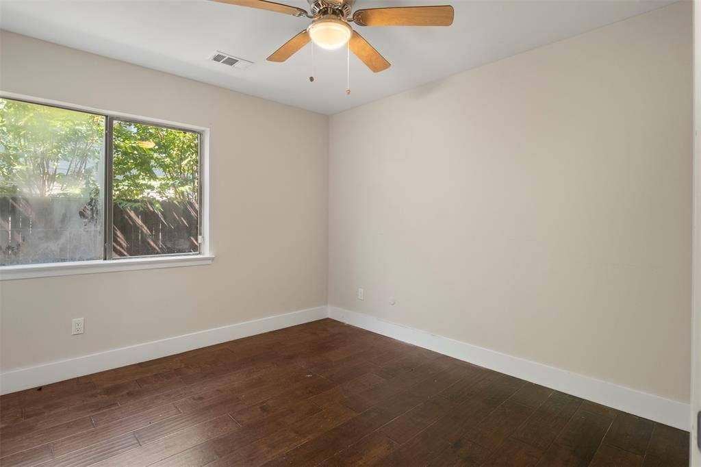 Hardwood-style flooring with white trim, a ceiling fan with integrated lighting, and a large window