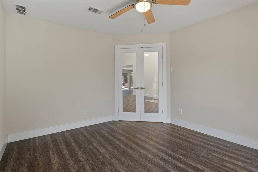 Wood-finish flooring, ceiling fan with integrated lighting, and double French doors with frosted glass panels