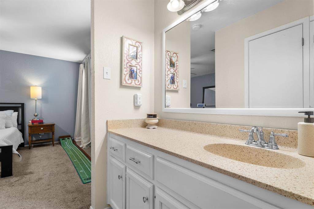 10712 Apache Drive, Waco, TX 76712 Bathroom vanity with a speckled countertop, undermount sink, dual-handle faucet, and white cabinetry