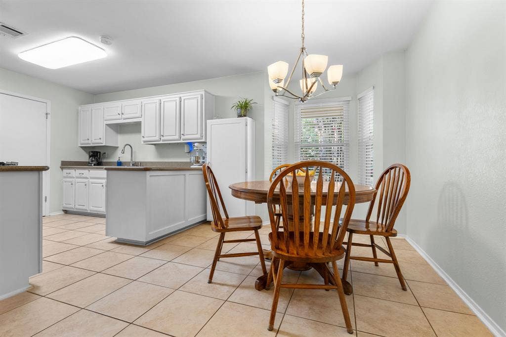 10712 Apache Drive, Waco, TX 76712 Tile flooring throughout, white cabinetry with a coordinating island, and a bay window