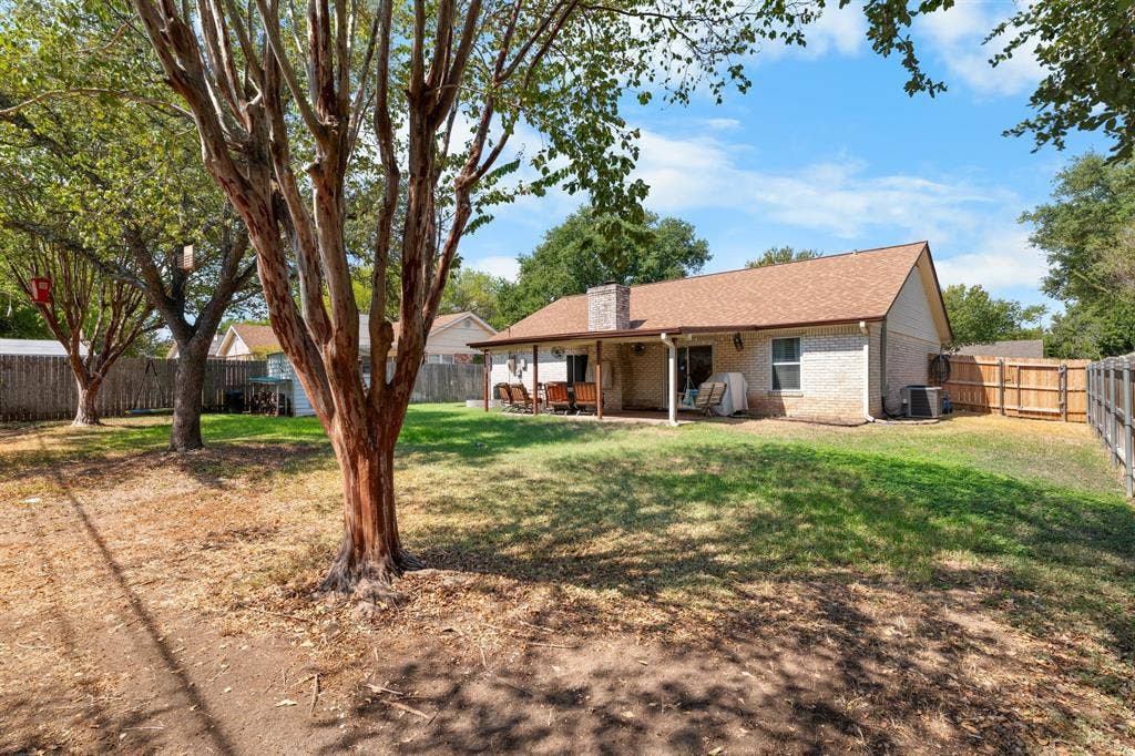10712 Apache Drive, Waco, TX 76712 Expansive backyard featuring mature trees, a covered patio, and a privacy fence
