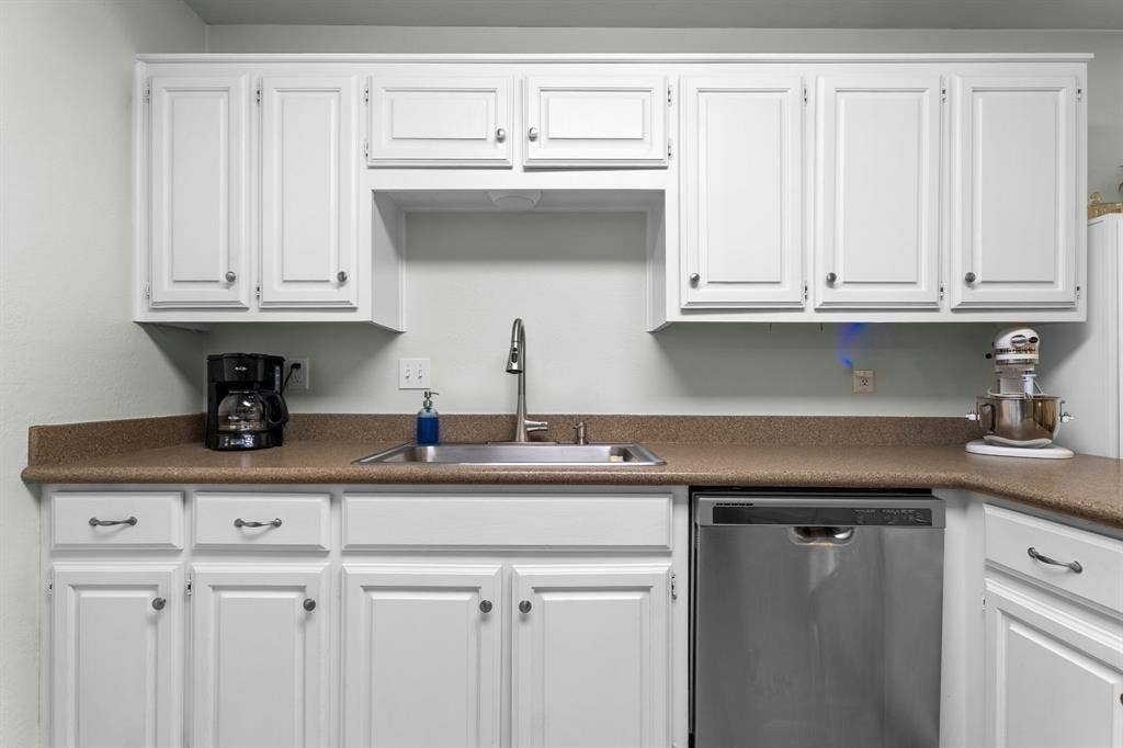 10712 Apache Drive, Waco, TX 76712 Bright kitchen featuring white cabinetry with recessed panel doors, warm wood-finish countertops, stainless steel appliances including a dishwasher, and a single-basin sink with chrome faucet