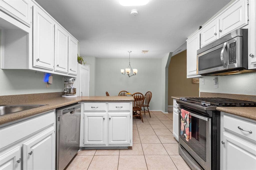 10712 Apache Drive, Waco, TX 76712 White cabinetry, stainless steel appliances, ceramic tile flooring, and solid surface countertops
