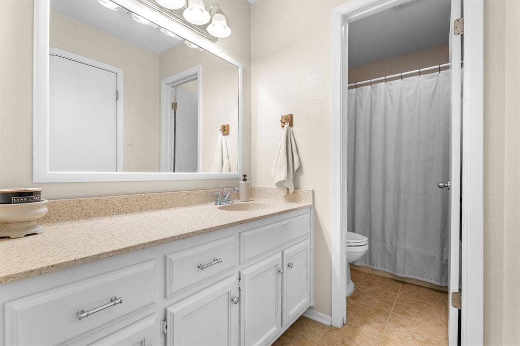 10712 Apache Drive, Waco, TX 76712 White vanity with chrome hardware, an integrated sink, and a light-toned countertop
