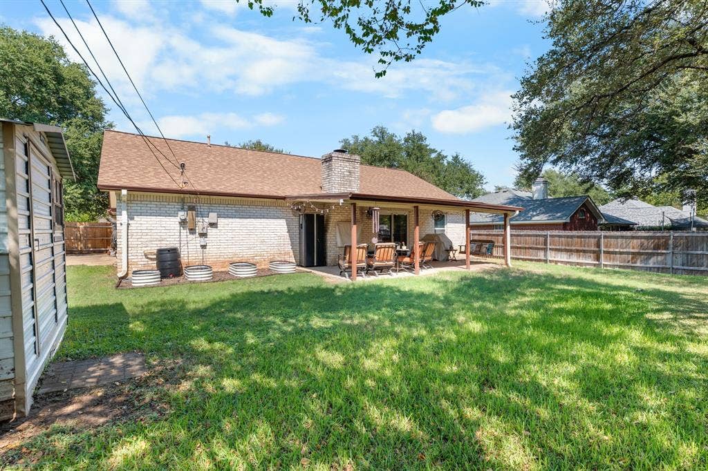 10712 Apache Drive, Waco, TX 76712 Expansive lawn with a covered patio, brick exterior, and a wood privacy fence