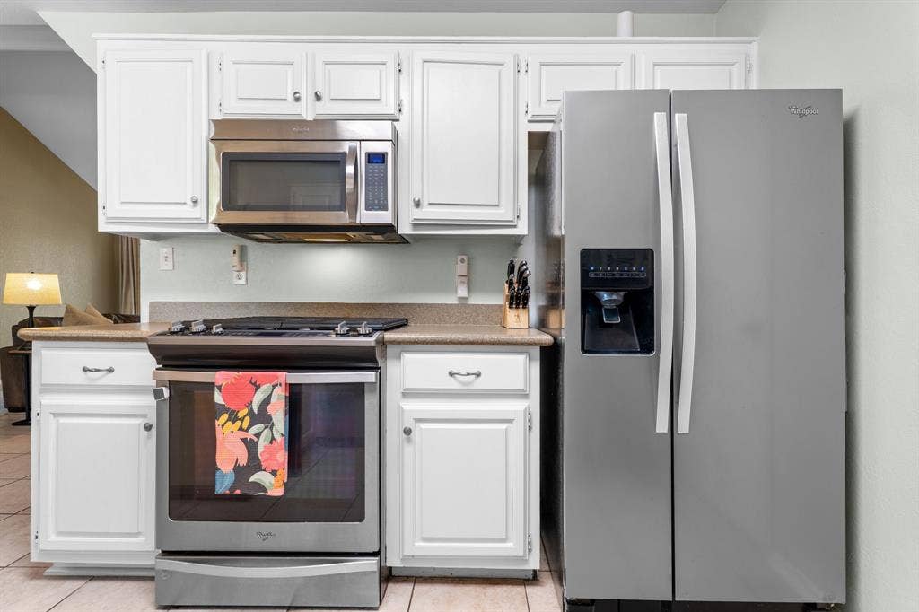 10712 Apache Drive, Waco, TX 76712 White cabinetry, stainless steel appliances, stone-finish countertops, and tile flooring