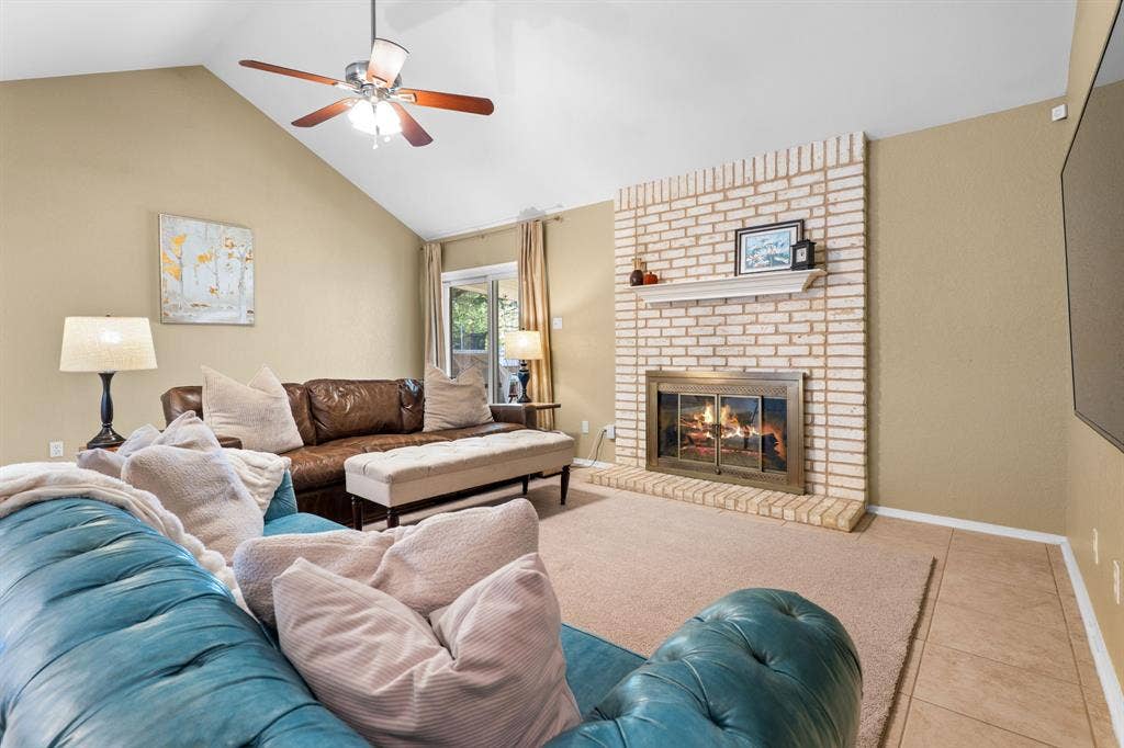 10712 Apache Drive, Waco, TX 76712 Vaulted ceiling with a ceiling fan, brick fireplace with a mantel, and sliding glass door