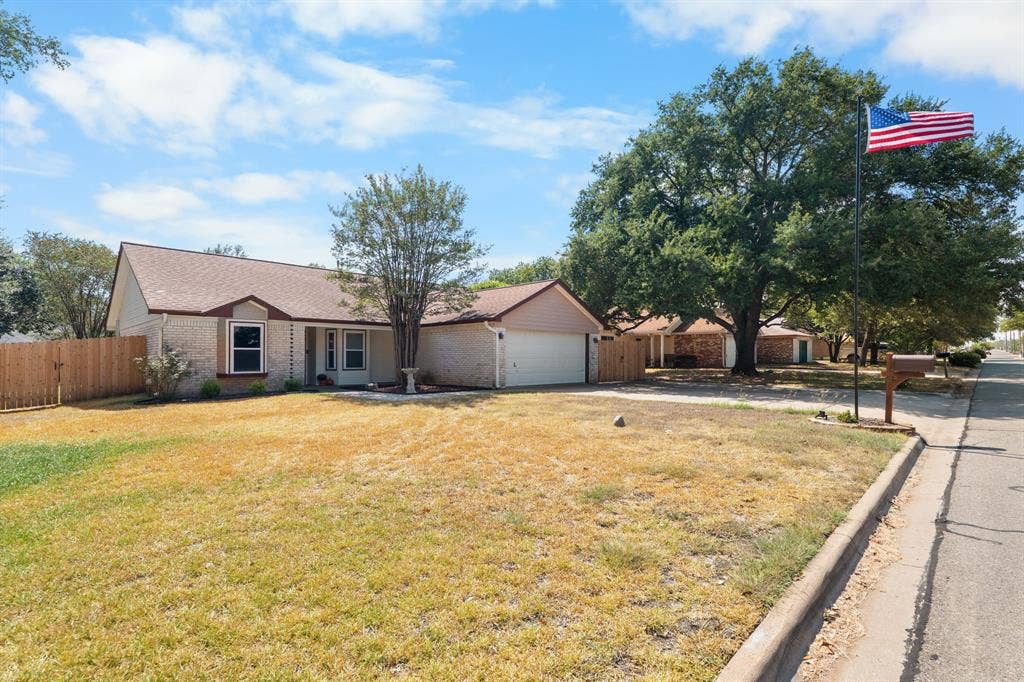 10712 Apache Drive, Waco, TX 76712 Brick exterior with an attached garage, a pitched roof, and a wooden privacy fence